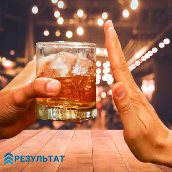 Рука протягивает стакан с алкогольным напитком